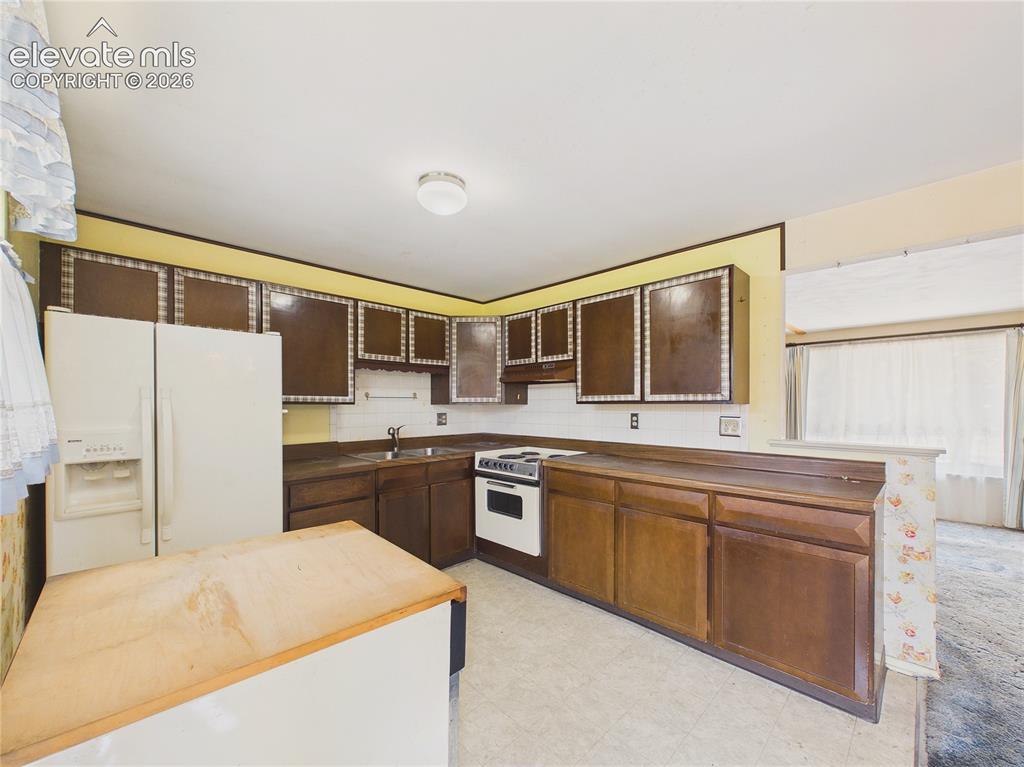 Image 12 of 50: Bright kitchen offers ample workspace, upper and lower cabinetry, and room 