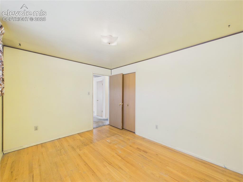 Image 18 of 50: Comfortable bedroom offers hardwood flooring, a large window for natural li