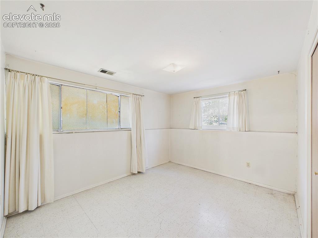Image 26 of 50: Bright lower-level bedroom features multiple windows, abundant natural ligh