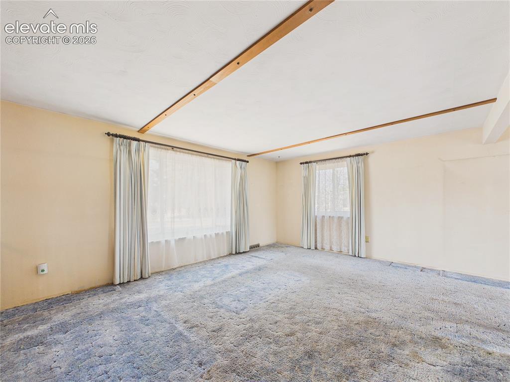 Image 4 of 50: Spacious living room filled with natural light from large windows, offering