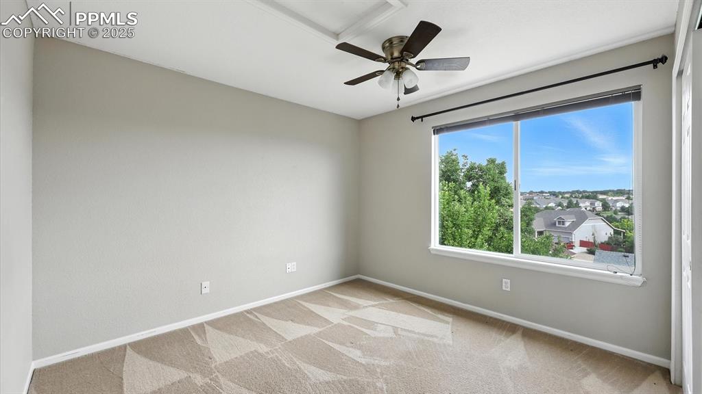Image 29 of 50: Upper level Bedroom #2 with neutral carpet, lighted ceiling fan, and large 