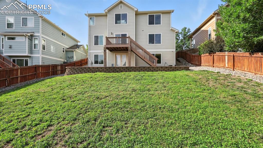 Image 48 of 50: Fenced backyard with auto sprinklers, wood deck, and flagstone patio.