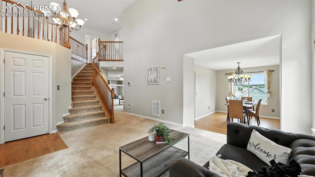 Image 8 of 50: The Living Room has stairs to the upper level and flows into the formal Din
