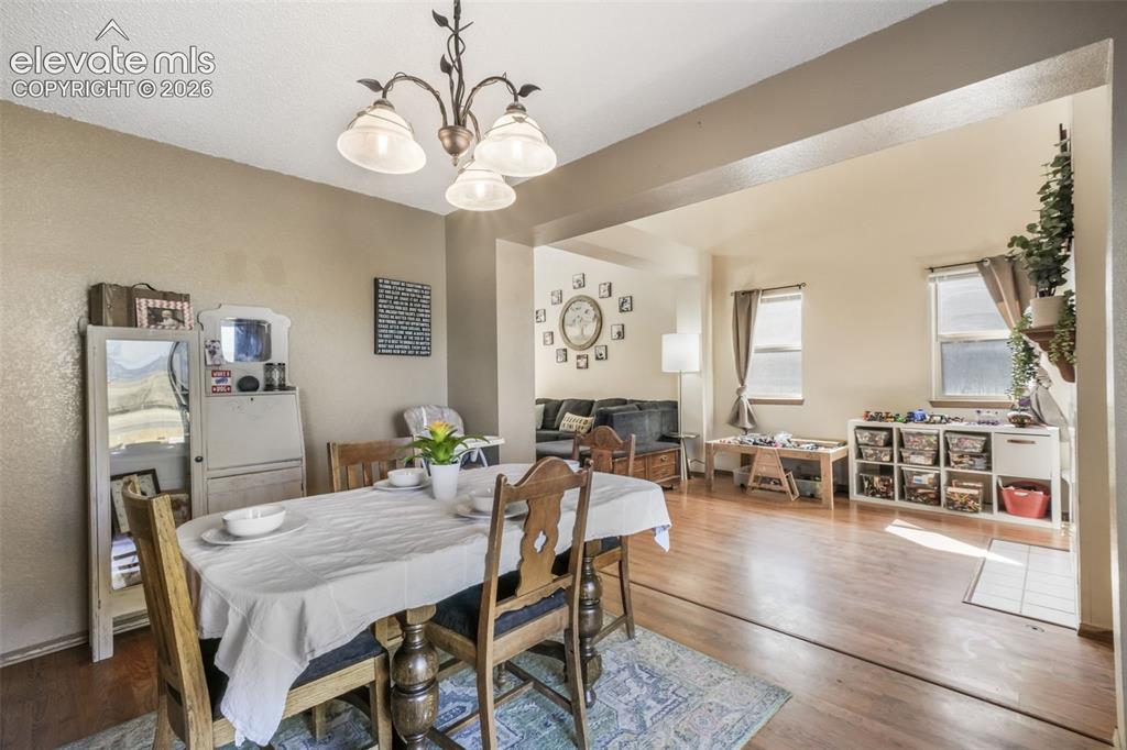 Image 12 of 50: Dining area featuring a bronze-finish chandelier with frosted glass shades,
