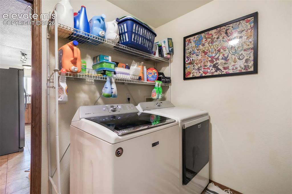 Image 18 of 50: Dedicated laundry area featuring a white top-load washing machine and white