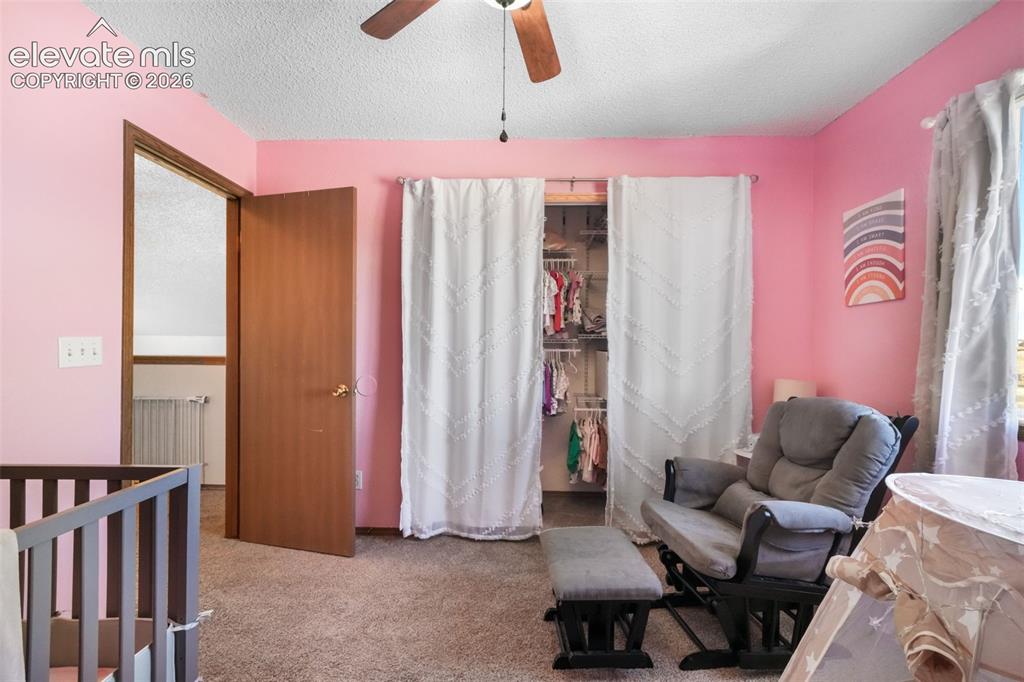 Image 22 of 50: Spacious room featuring a ceiling fan, carpeted flooring, and a large windo