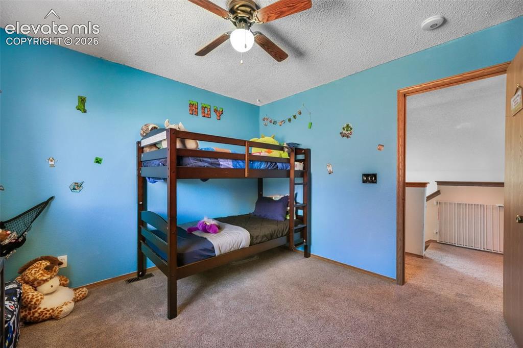 Image 25 of 50: Carpeted room featuring a ceiling fan with light fixture and a wood-trim do