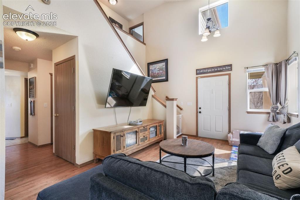 Image 3 of 50: Living area with wood-finish flooring, vaulted ceiling, and an upper-story