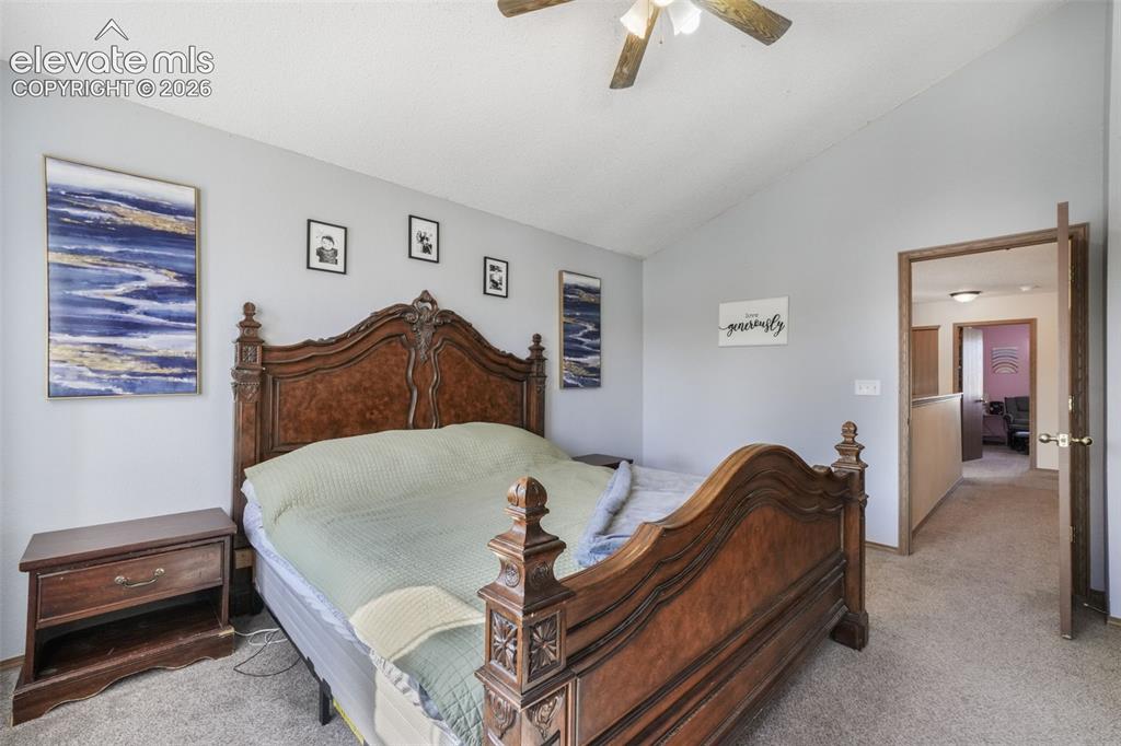 Image 31 of 50: Vaulted ceiling with a ceiling fan, light gray wall paint, and gray carpet