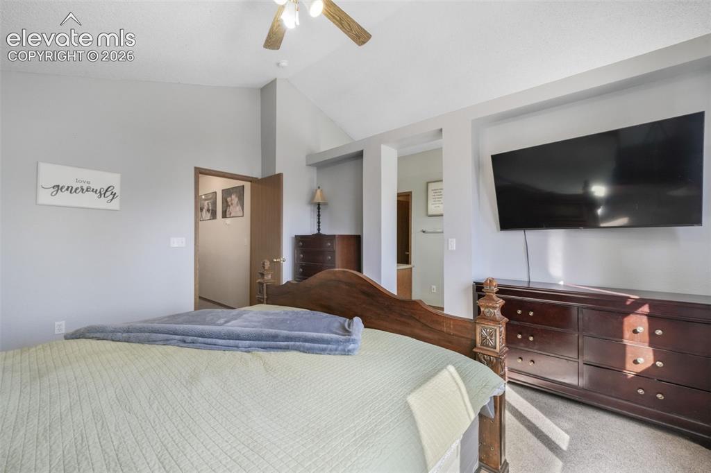 Image 32 of 50: Vaulted ceiling bedroom with ceiling fan, light gray wall paint, and carpet