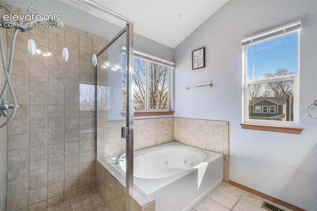 Image 34 of 50: Bathroom featuring a glass-enclosed shower with tile surround, a built-in j