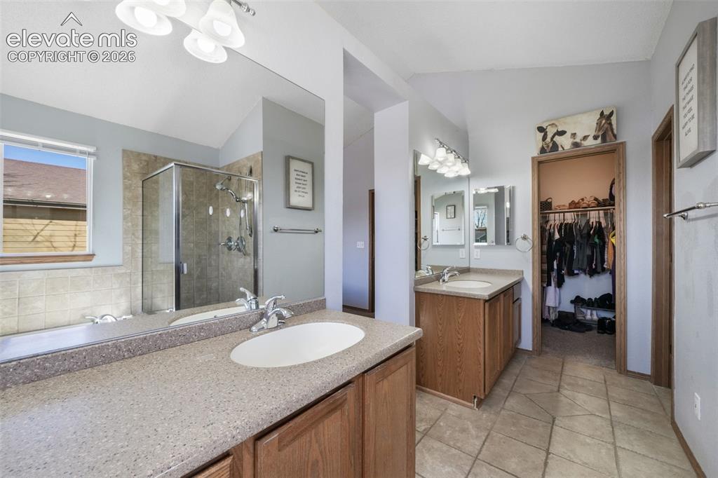 Image 35 of 50: Spacious bathroom featuring dual vanities with solid surface countertops, a