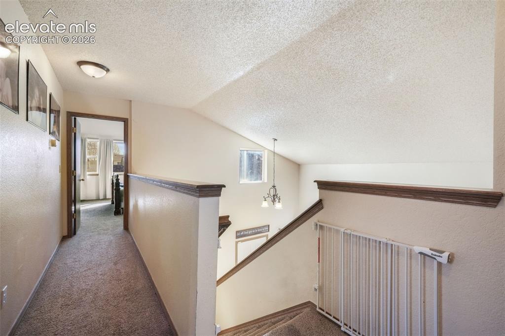 Image 37 of 50: Upper-level hallway with textured walls and carpet flooring
