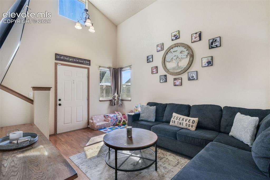 Image 4 of 50: Living area featuring high ceilings, wood-finish flooring, a prominent skyl