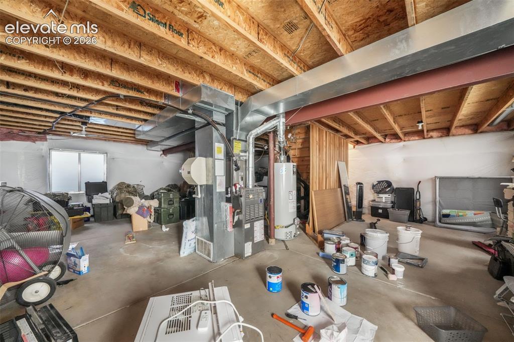 Image 40 of 50: Unfinished basement space with exposed wood joists and concrete flooring, f