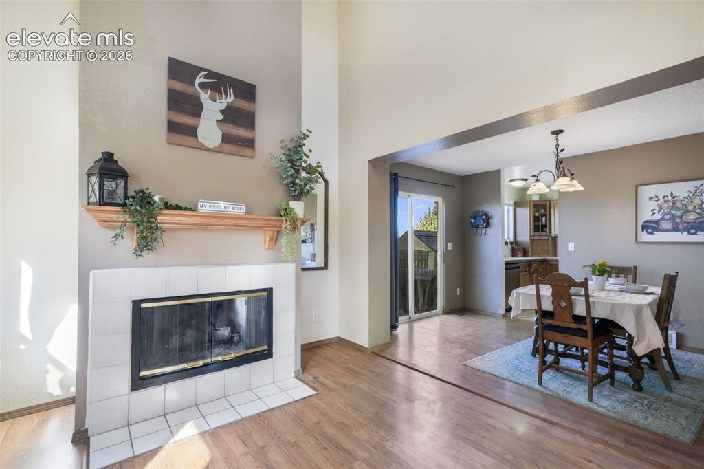 Image 8 of 50: Living area with a white tiled fireplace and natural wood mantel