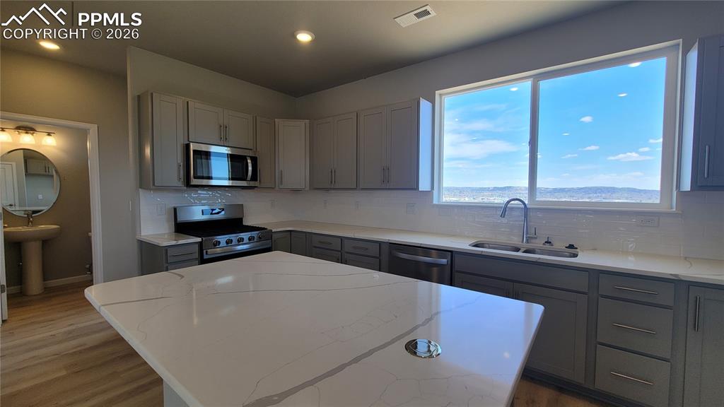 Image 12 of 39: Kitchen with quartz countertop, pantry, large island providing additional s