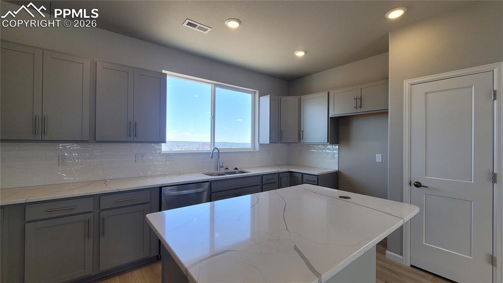 Image 13 of 39: Kitchen with quartz countertop, pantry, large island providing additional s